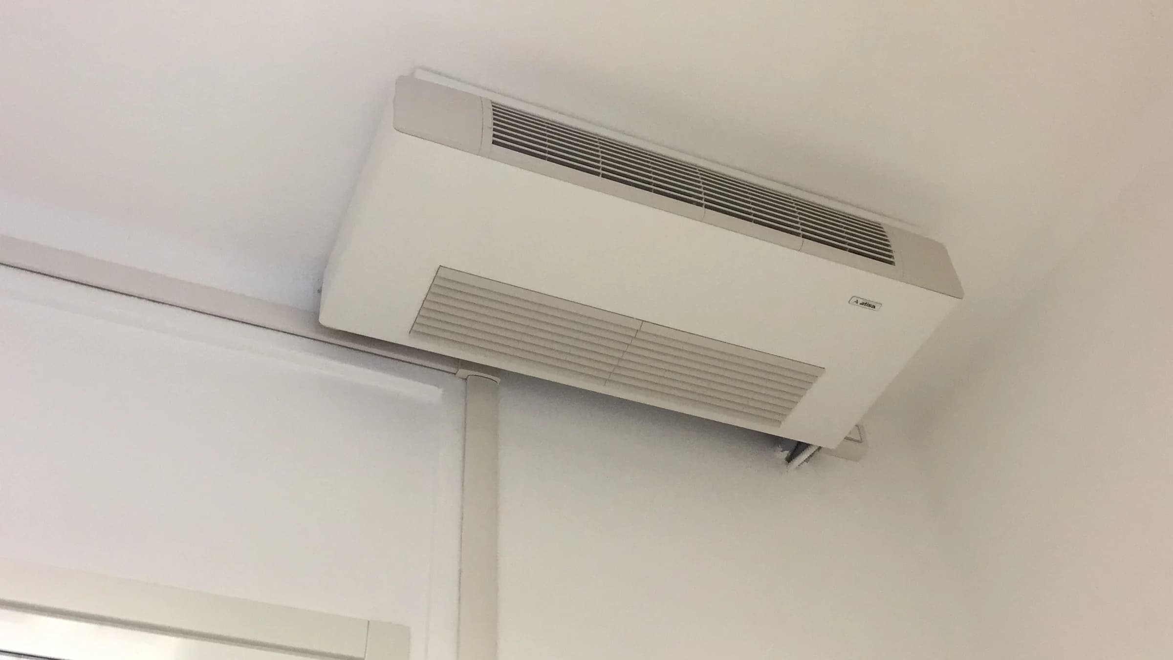 A ceiling-mounted fan coil unit with visible intake and discharge grilles