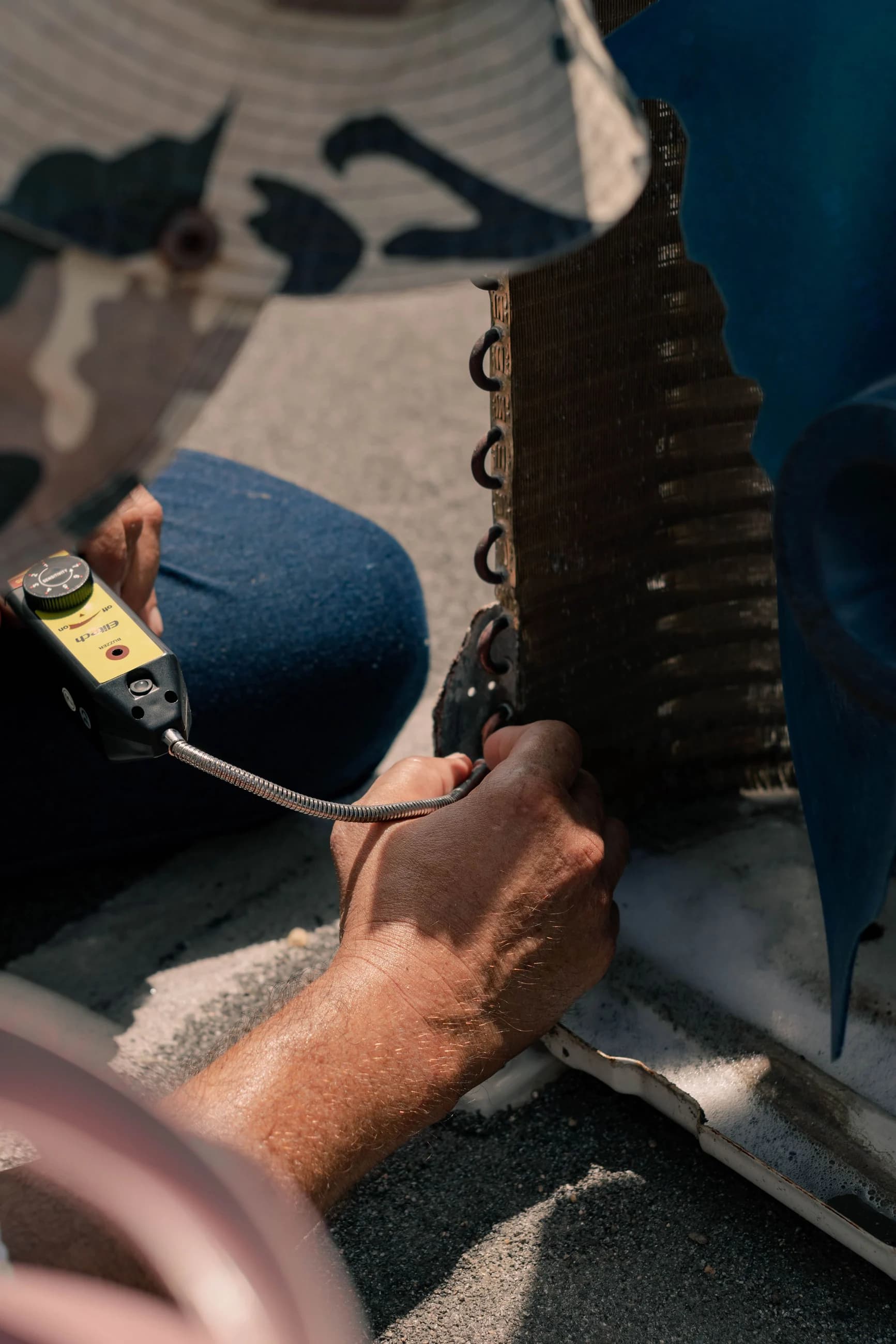 Close-up of a technician checking an air-conditioning coil with a handheld service instrument