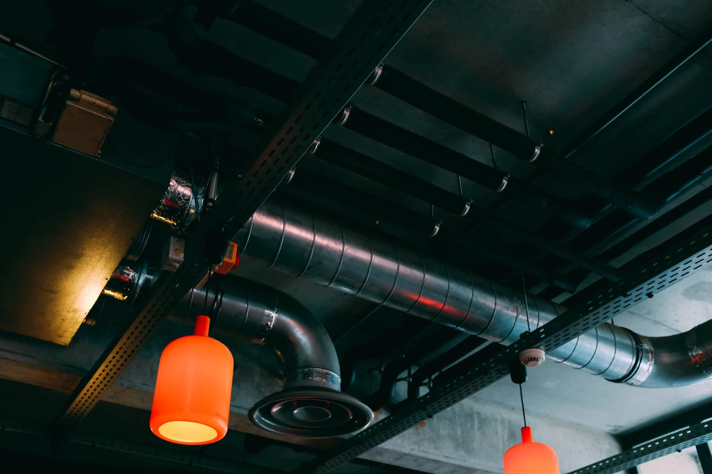 Circular ventilation ductwork and an air diffuser alongside suspended lights and ceiling services