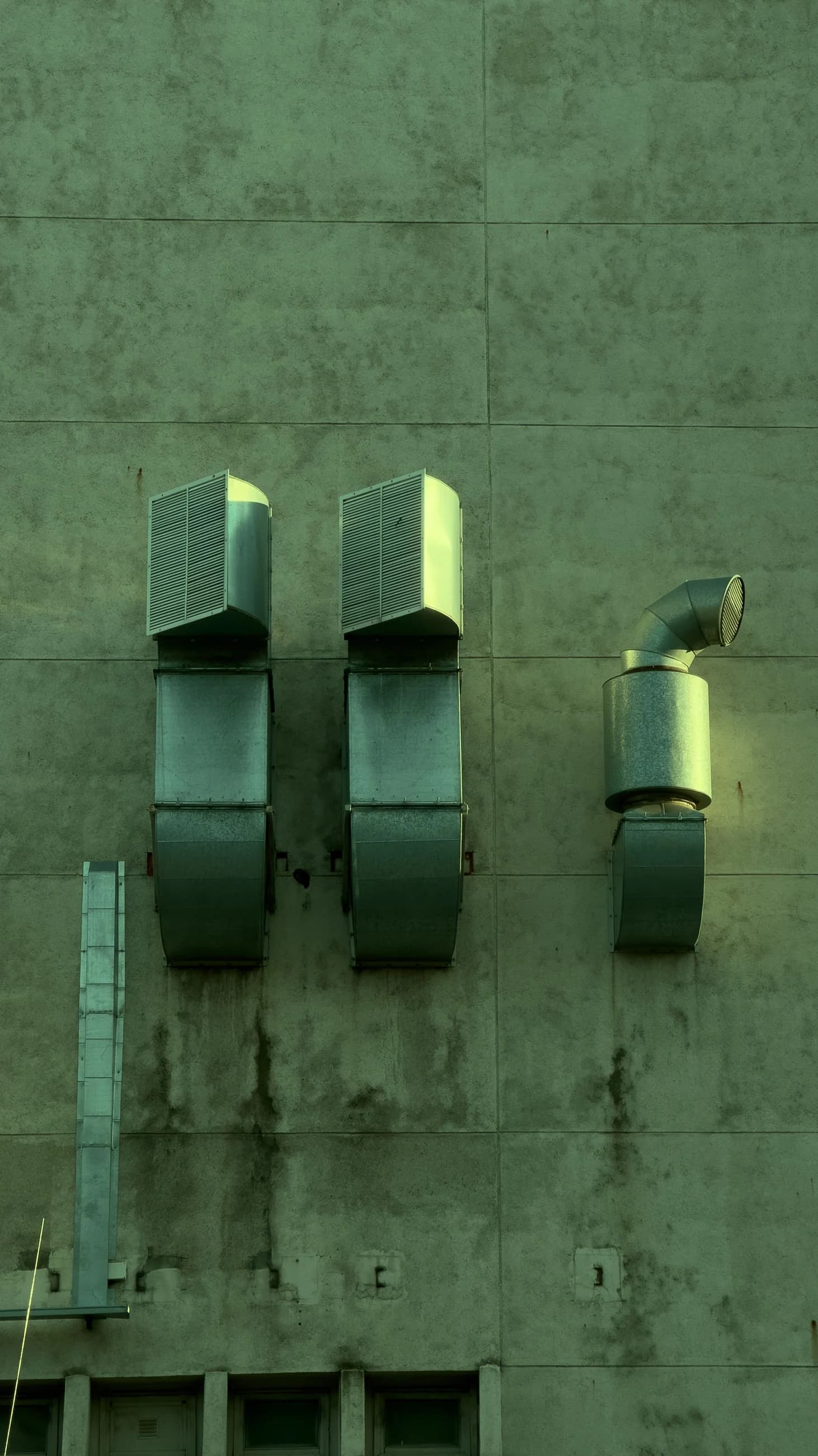 External metal exhaust ducts and outlet hoods mounted on a building wall