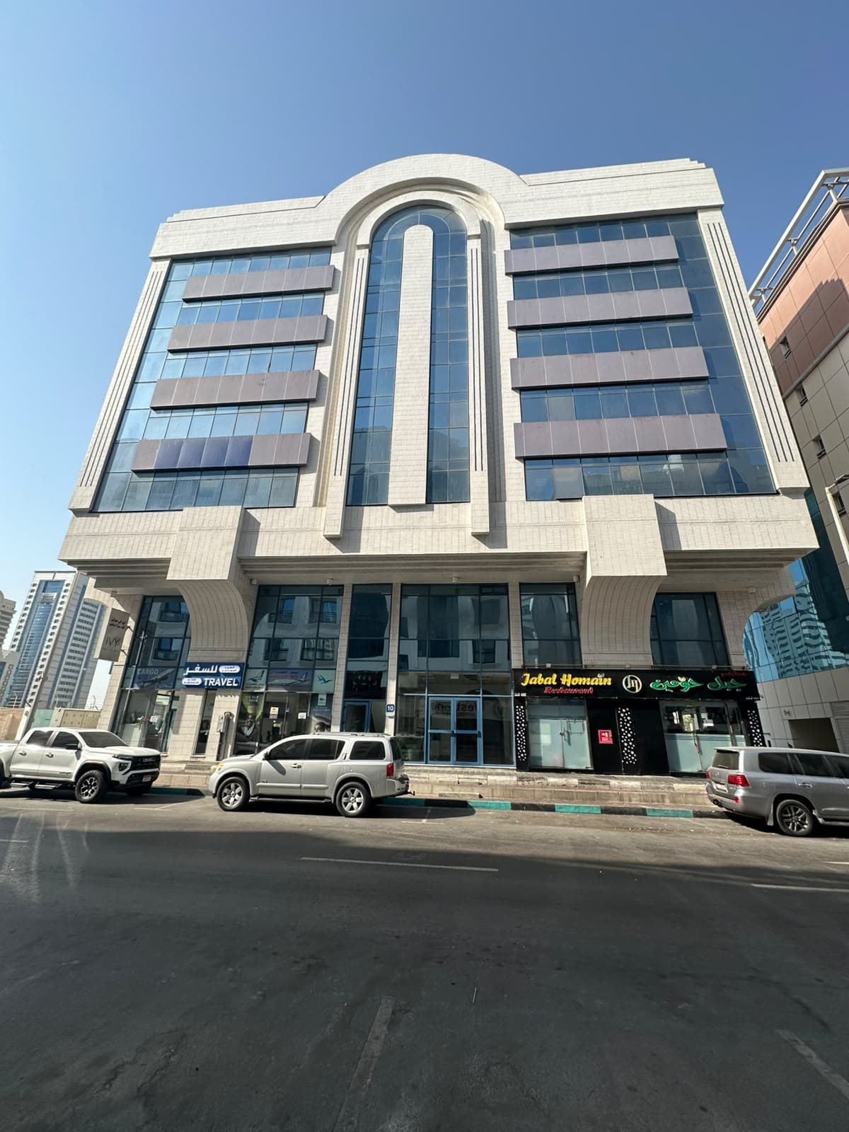 الواجهة الأمامية لمبنى الملا بطوابق علوية زجاجية ومحلات في الطابق الأرضي