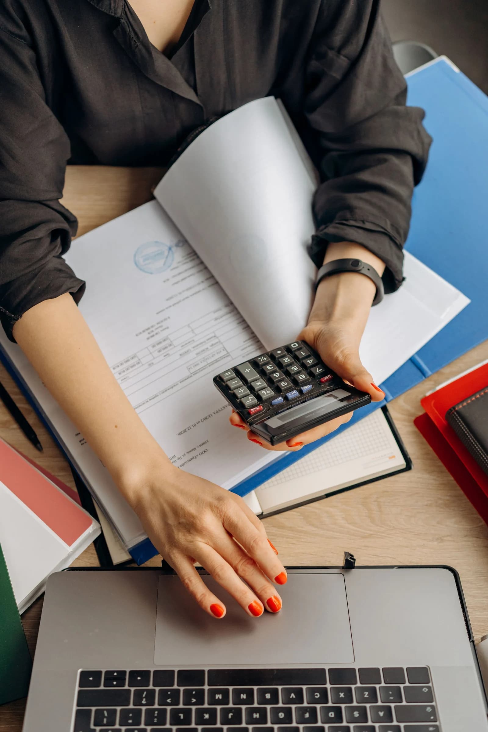 موظفة إدارية تراجع الرسوم الموثّقة باستخدام آلة حاسبة وحاسوب محمول