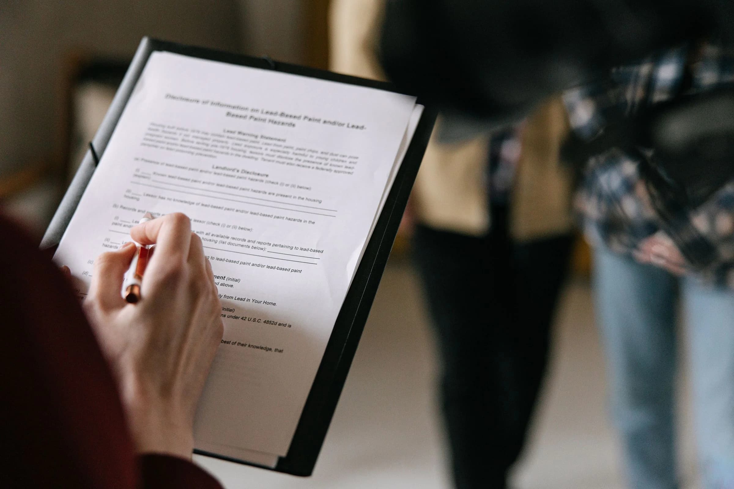 Close-up of a client signing property agreement paperwork