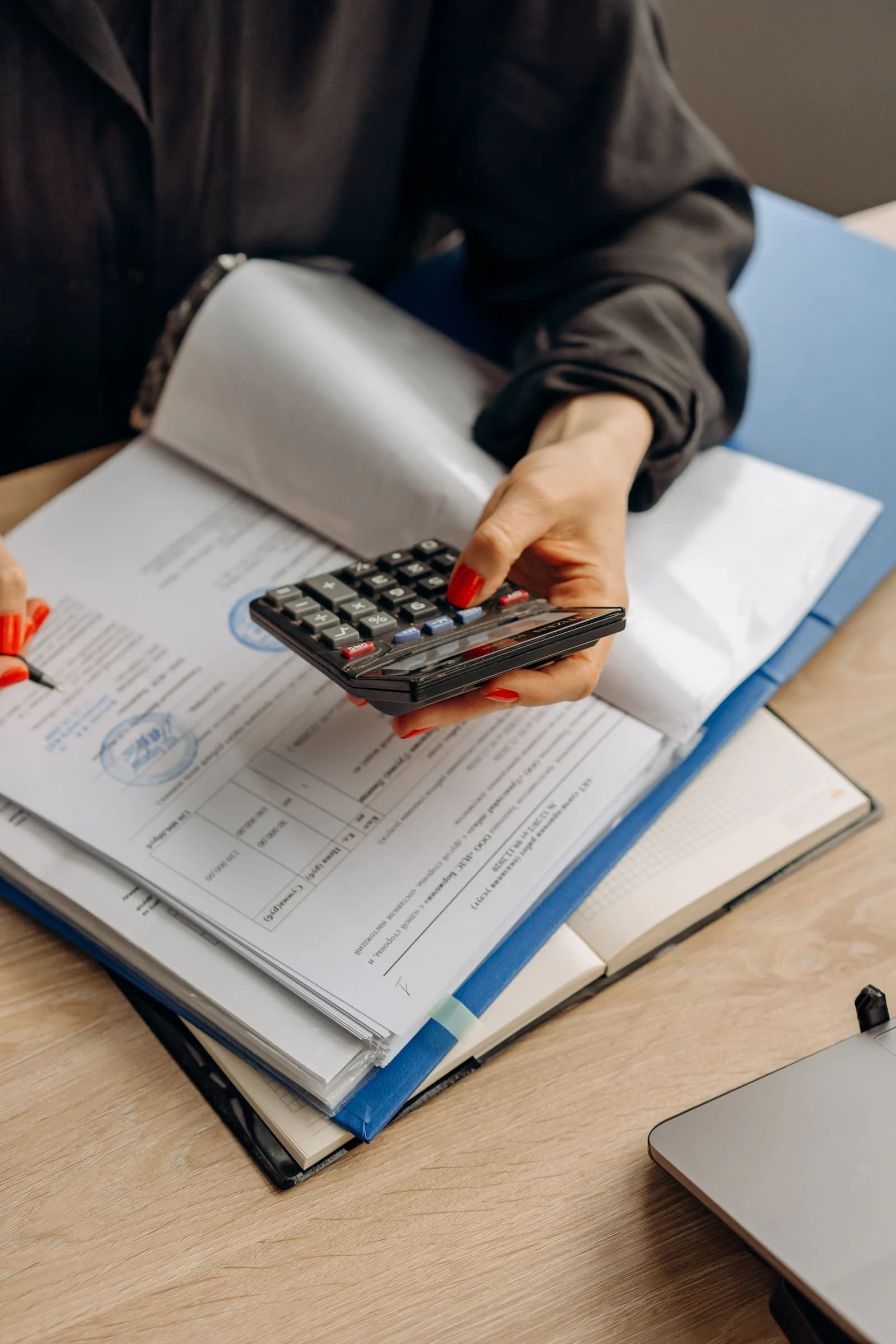 Administrator checking payment records with a calculator and document folders