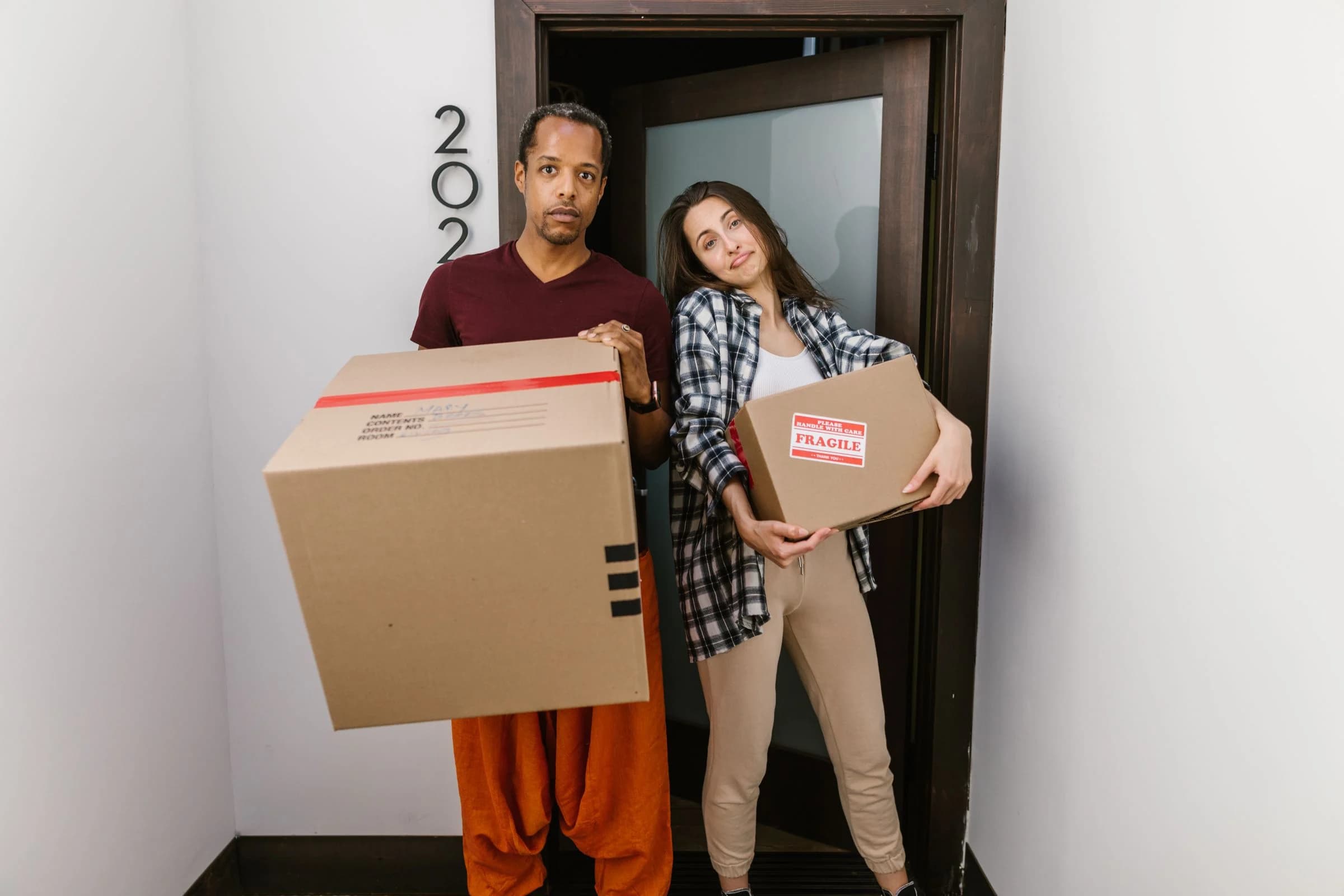 Residents carrying moving boxes through an apartment doorway