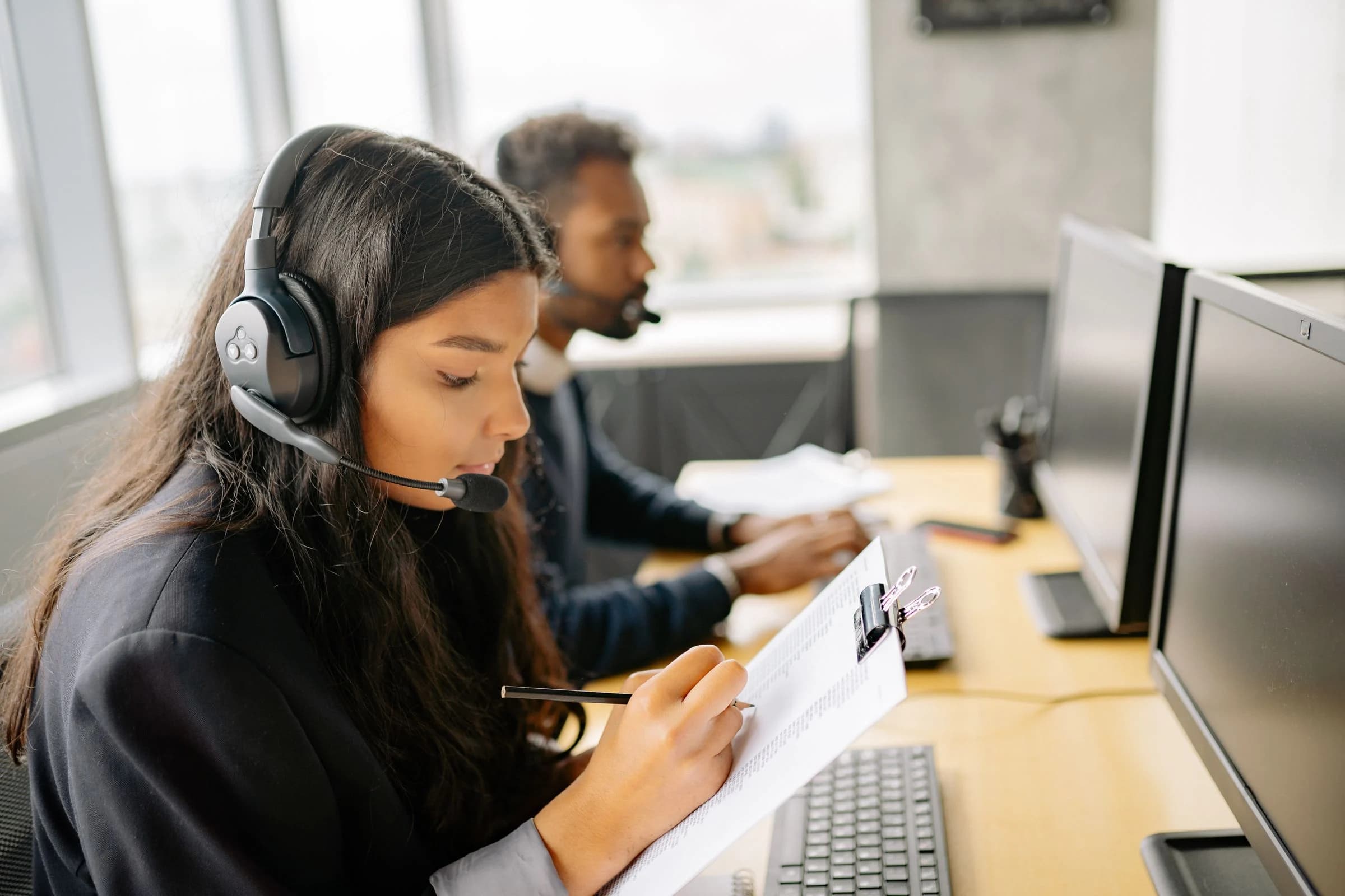 Support advisor taking notes on a clipboard during a client call